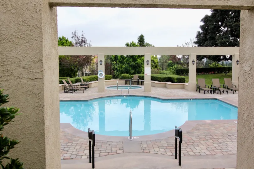 There are some chairs beside the swimming pool in a garden area in California Renaissance