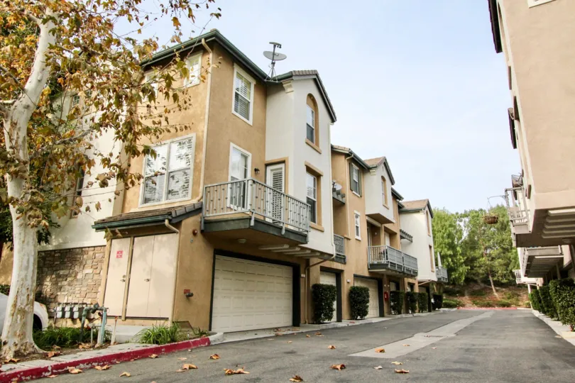 Attached homes with single and double car garages under units with stucco siding and a wide back lane at Camden Park
