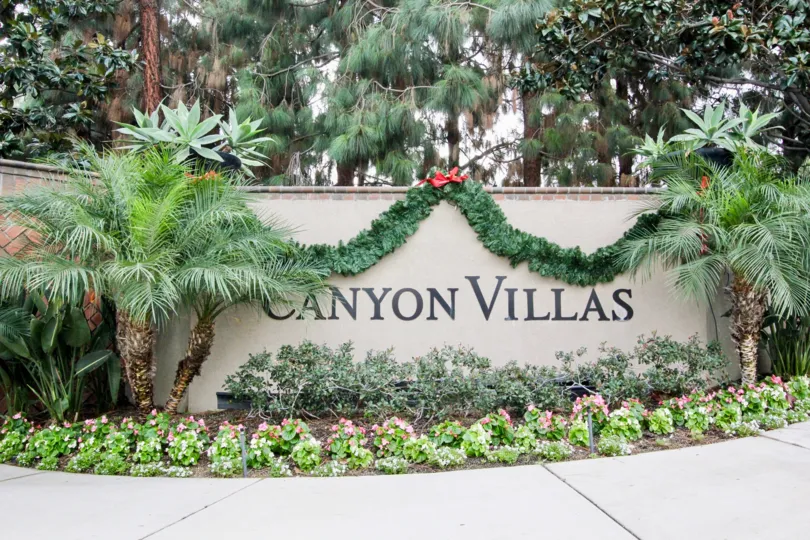Plants and garland draped over entry sign at Canyon Villas in Aliso Viejo, California