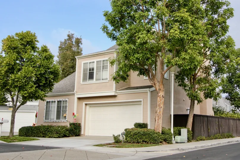 A dusty pink two story home surrounded by trees in the Cape Series community of California.