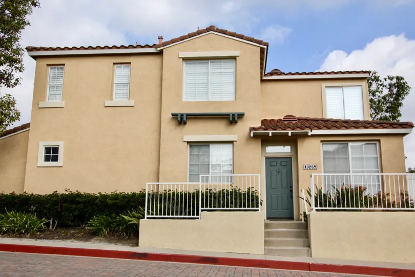 A white fence in front of a two story condominium complex inside the Florest Los Alisos in Aliso viejo CA