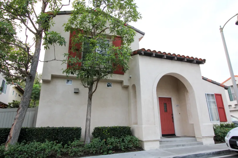 A sweet beautiful wight color house in the Greystone Colony with some shrubs and tree.