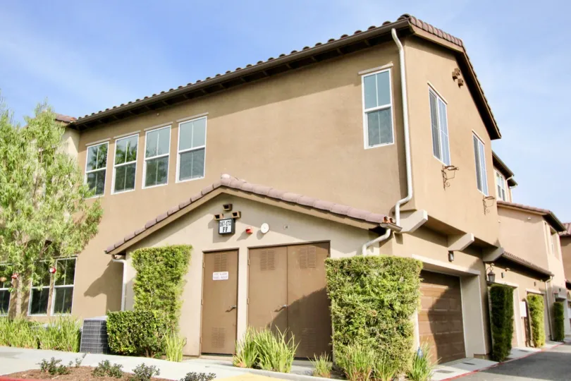Sunny sky with a building and bushes and garages in the Harbor Station Community in Aliso Viejo, CA.