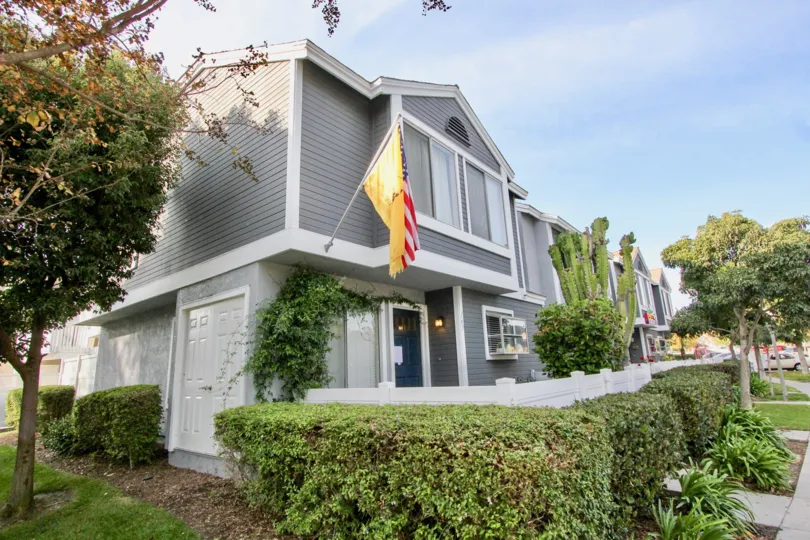 Flags hang beisde this smartly painted Morningshide Terrace home, surrounded by verdant bushes and a crisp white fence.
