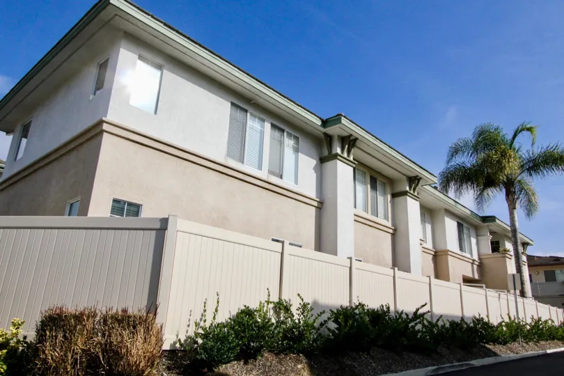 Building with sa sunny sky and a fence and a tree in the Orleans Community in Aliso Vieja, CA.