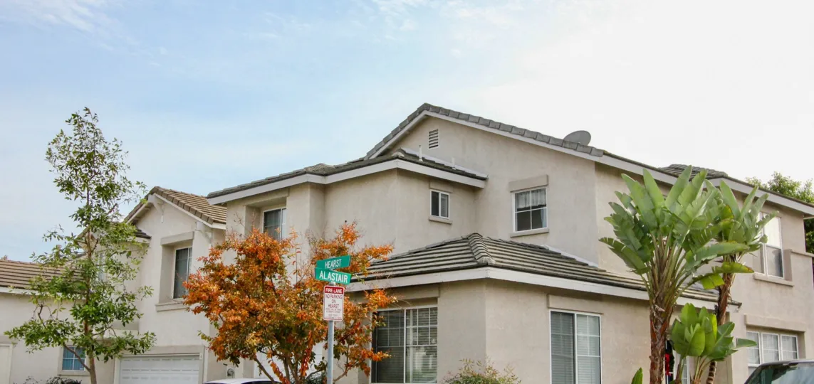 A large, offwhite home is surrounded by different types of trees in San Simeon.