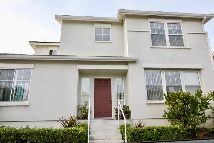 House with a cloudy sky and bushes in the San Simeon Community in Aliso Viejo, CA.