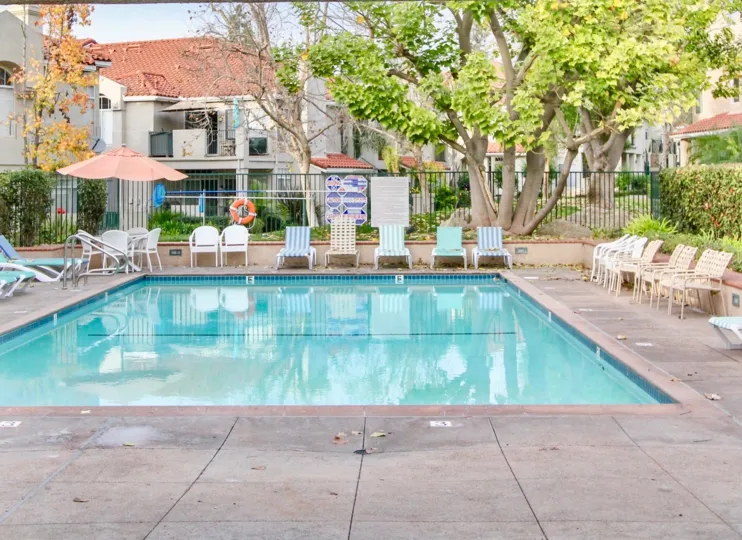 A clear blue pool, surrounded by lounge chairs and foliage, in Seagate Colony.