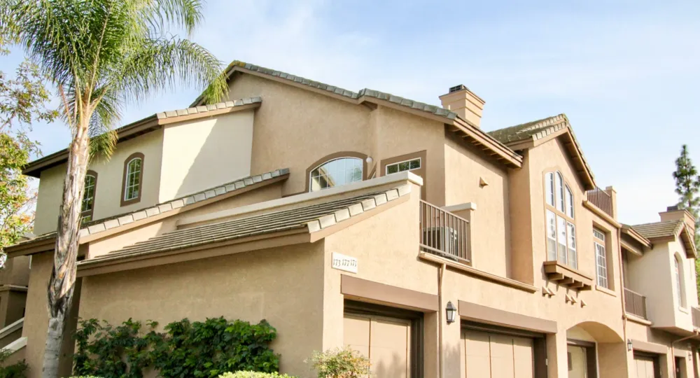A Spanish style St. Tropez home, painted a soft coral hue, with a palm tree in the yard.