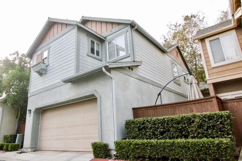 This is a gray house with salmon colored trim and garage with a nice private enclosed patio area