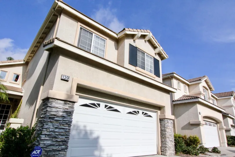 A two story home with navy shutters and stone column accents in California's Victoria community.