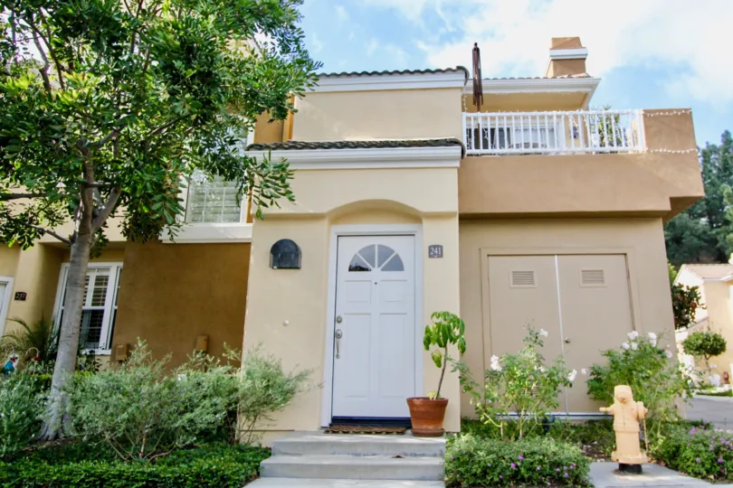 a pleasant day in the villas south with ahouse that has a tree in front and a small flower pot next to the door