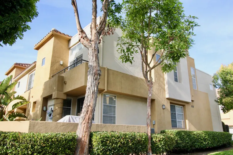 Sunny sky with a building and trees and bushes in the Windsong Community in Aliso Viejo, CA.