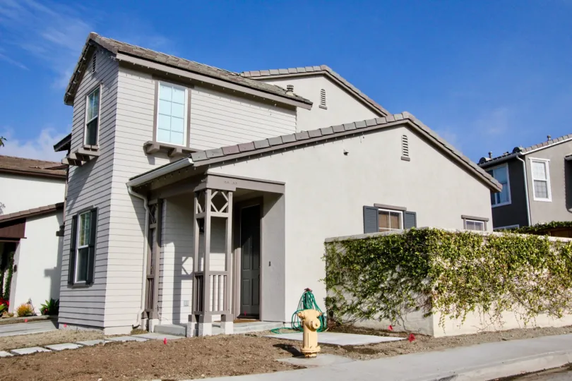 Sunny sky with a two story building and a fence with vines in the Woodlands community in Aliso Viejo, CA.