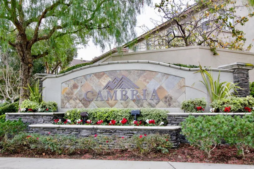 A large marble and cement community wall with colorful flowers outside Cambria in Anaheim HIlls California