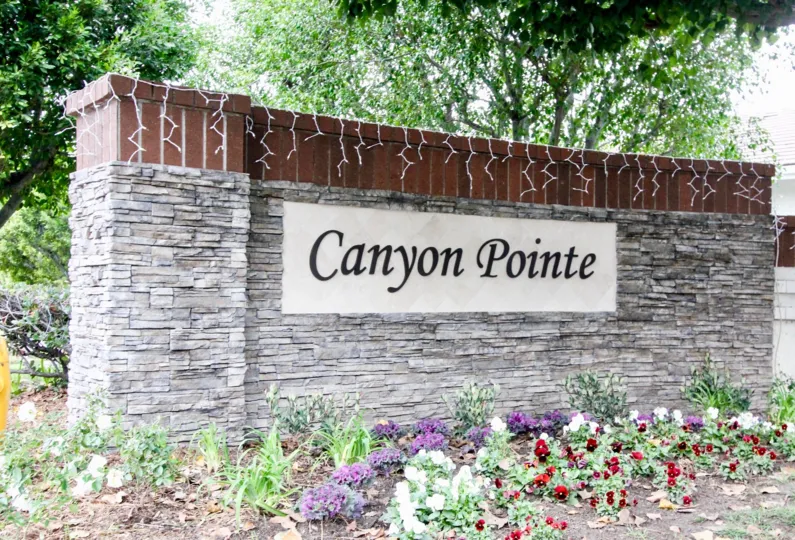 wall have board Canyon Pointe and the wall decorated with flowers in front in Canyon Pointe
