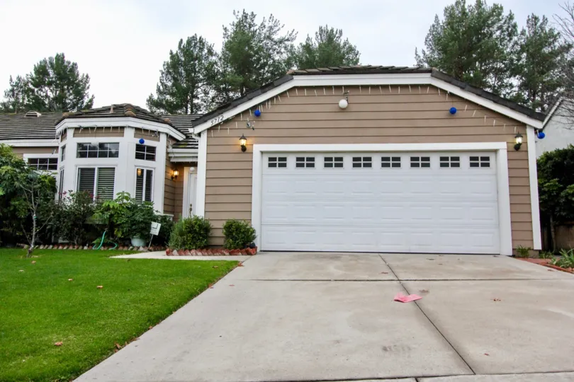 THIS SHOWS THE HOUSE WITH SHED WHICH IS IN CROWN POINTE, THAT HAS BEAUTIFUL LAWN NEARBY MANY PLANTS ARE SHOWN