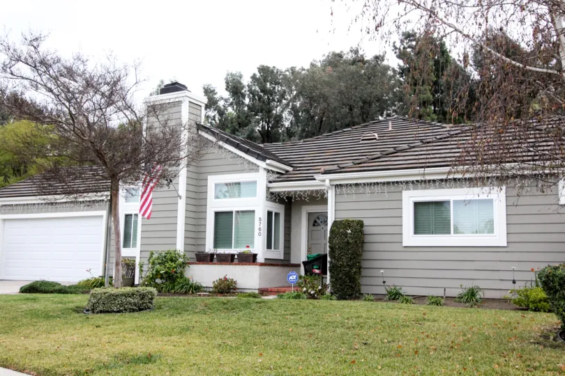 THIS IMAGE VIEWS THE FRONT OF THE HOUSE THAT HAS THE DOOR NUMBER ON THE WALL, SHOWS GLASS WINDOWS, BEAUTIFUL LAWN, TREES, PLANTS IN THE CROWN POINTE