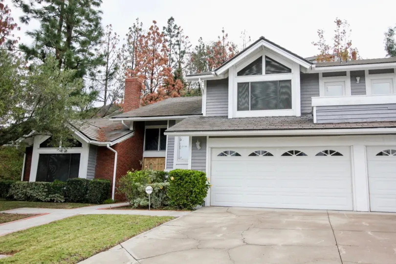 THE FRONT VIEW OF HOUSE WITH SHETTER, LAWN, SMALL PLANTS, TREES ARE THERE IN THE CITY OF ANAHEIM HILLS