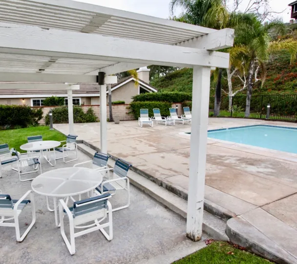 A sunny day in the area of Horizons, pool, beach chairs, palm trees, patio, table, grass, condo