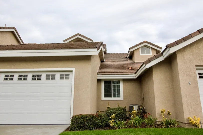 a brown coloured house with dark brown roof and white garage d oor