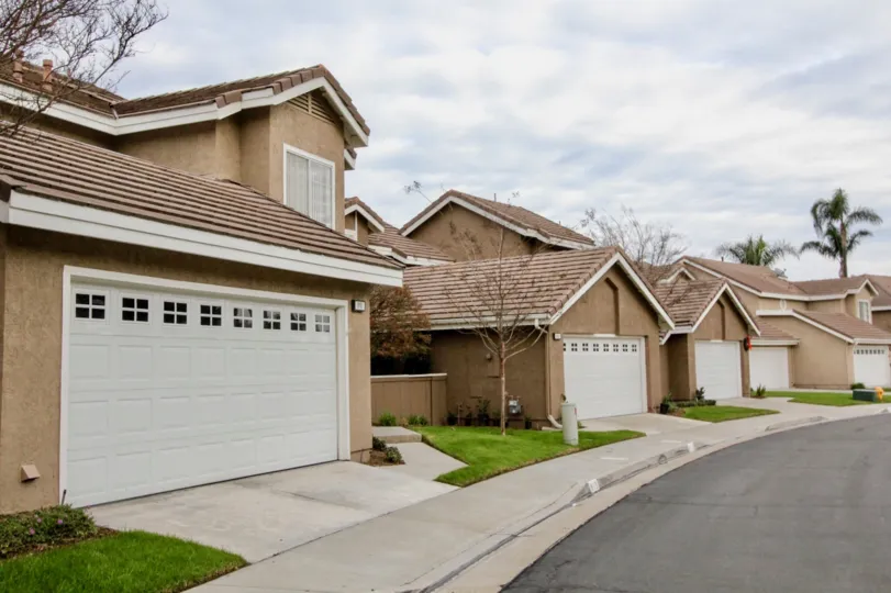 line of houses with garage doors in front and a pathwalk with grass in middle
