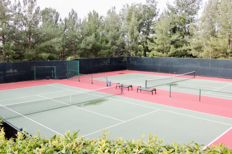 Tall green trees surrouds Monaco tennis court, Anaheim HIlls, CA