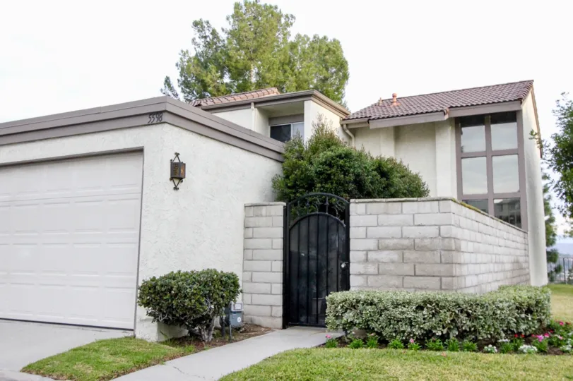 a house entrance with a black door a garage on side and grass with bushes around
