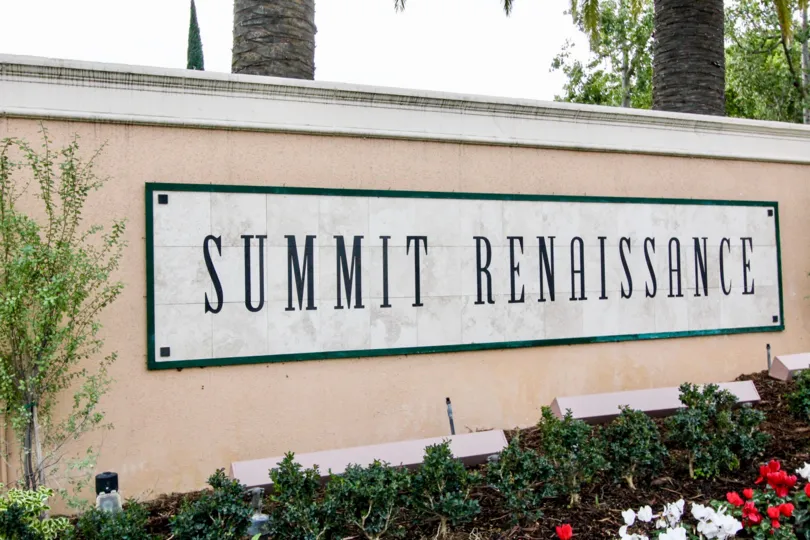 summit renaissance sign on a half wall with roses and flowers below