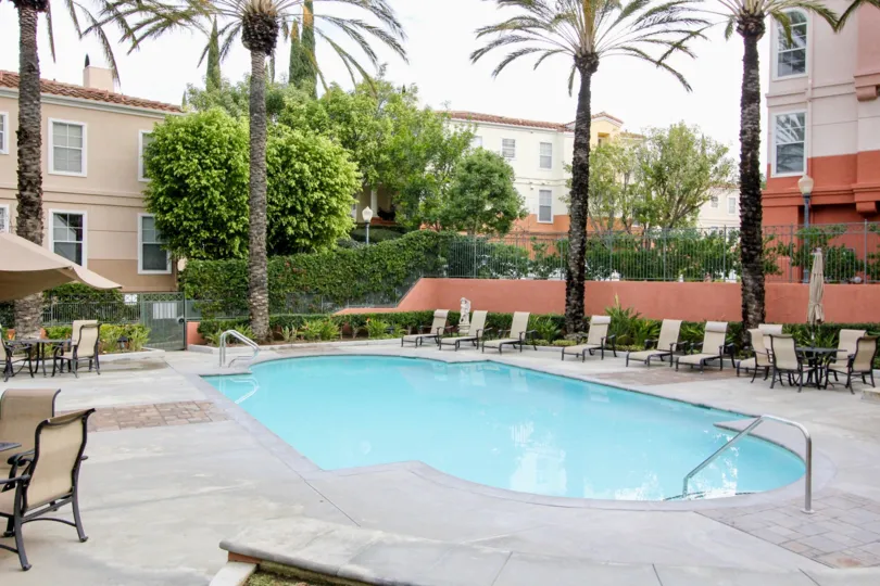 THIS IMAGE SHOWS THE SWIMMINGPOOL WHICH IS LOCATED IN ANAHEIM HILLS, WHICH HAVE THE CHAIRS, TREES, PLANTS ARE THERE