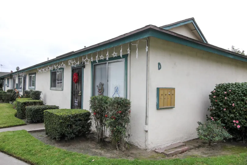 A one floor white stone house has bushes out front in Anaheim, California.