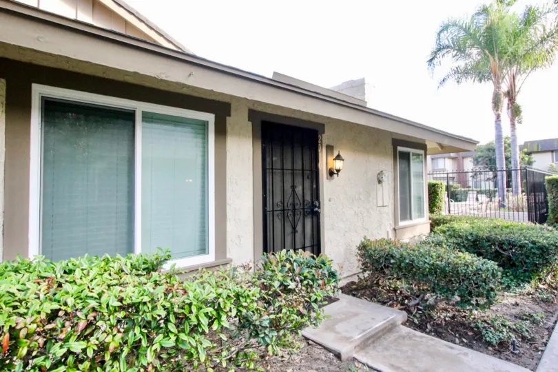A beautiful house in the Anaheim Gardens with some shrubs, tree and foot path.