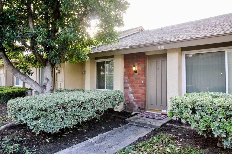 a home with a gray door and brick front and a concrete walkway in Anaheim Gardens
