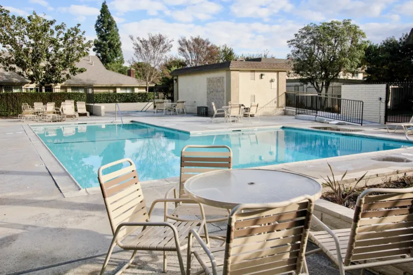 Scene of a pool with tables and chairs at Anaheim Gardens in Anaheim, California