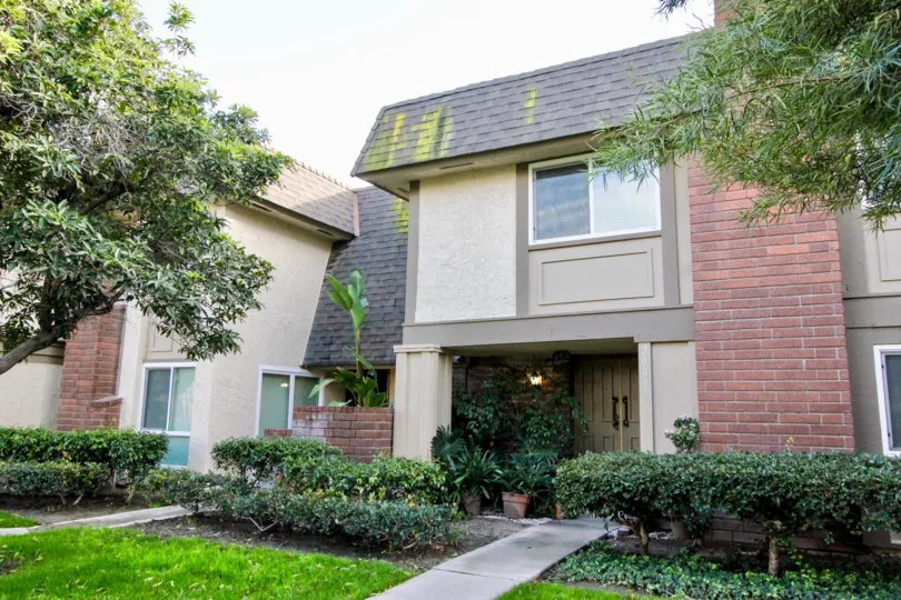 THE FRONT OF THE HOUSE WITH LAWN, CROTON PLANTS, TREES LOCATED IN ANAHEIM CITY