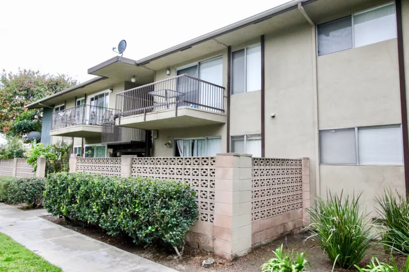 An apartment complex with fenced balconies and a brick privacy wall in Anaheim, CA