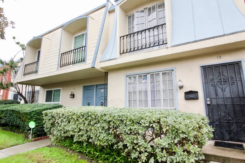 The entrance to homes in Anaheim Village III showing landscaping and balconies