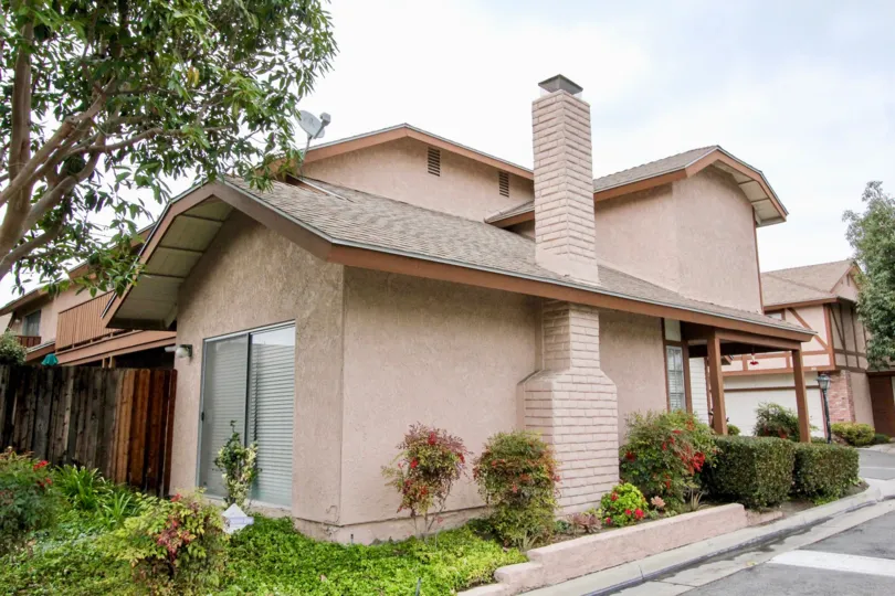 THE SIDEVIEW OF THE HOUSE WITH PLANTS WITH FLOWERS, ROAD WAY, DISH ARE SEEN IN ANAHEIM CITY