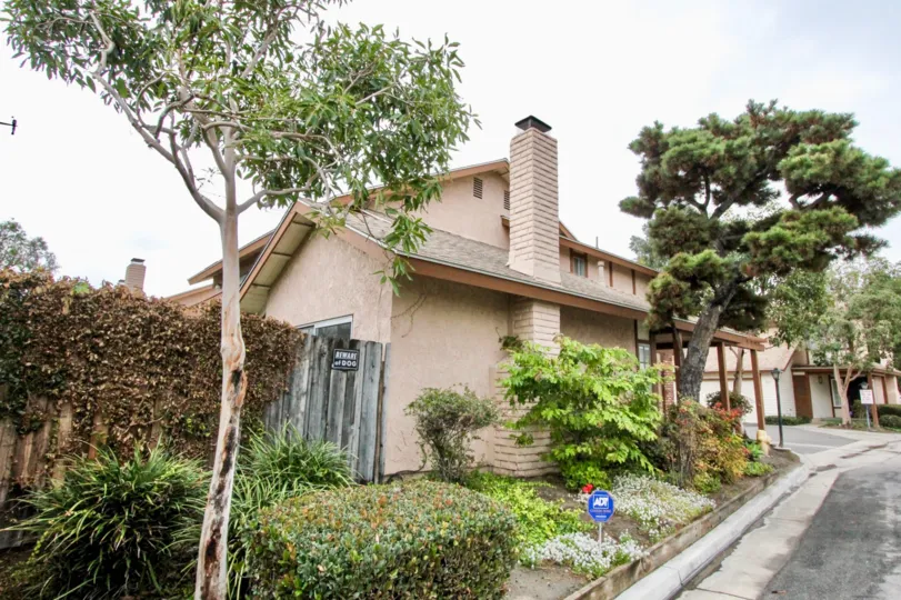 An overcast day at a house in Anaheim California with trees and a road.