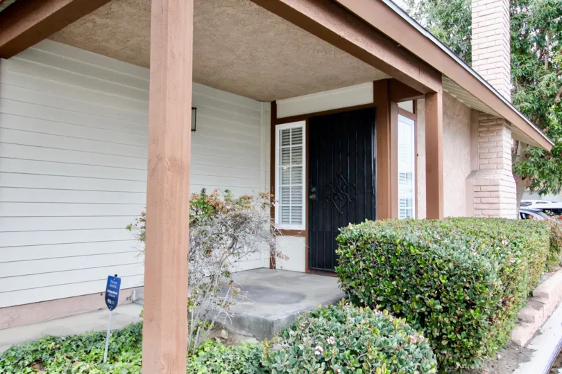 Front door of a house with chimney and bushes at the side