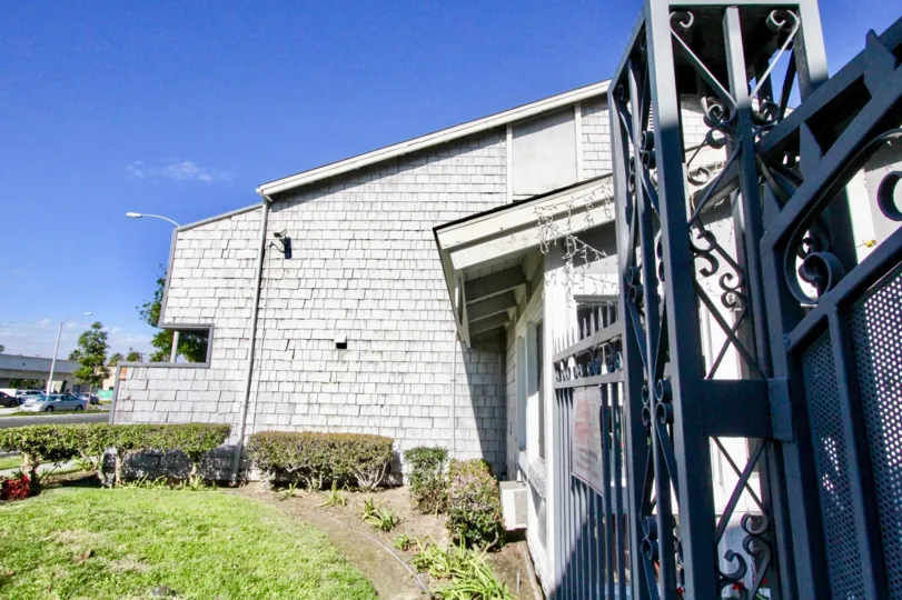 A WARM DAY IN THE Brookhurst Village WITH A BUILDING THAT HAS CLOSED THE DOOR AND SIDE OF GARDEN AND OPPOSITE SIDE ROAD AND ONE CAR ON THE ROAD