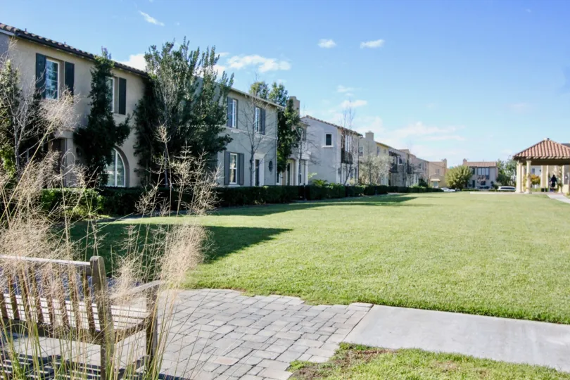 A series of two-storey townhouses in the Cantada Square community in front of a spacious yard.