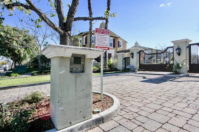 A pillar with a meter in the Cantada Square community with paved driveway and steel gates.