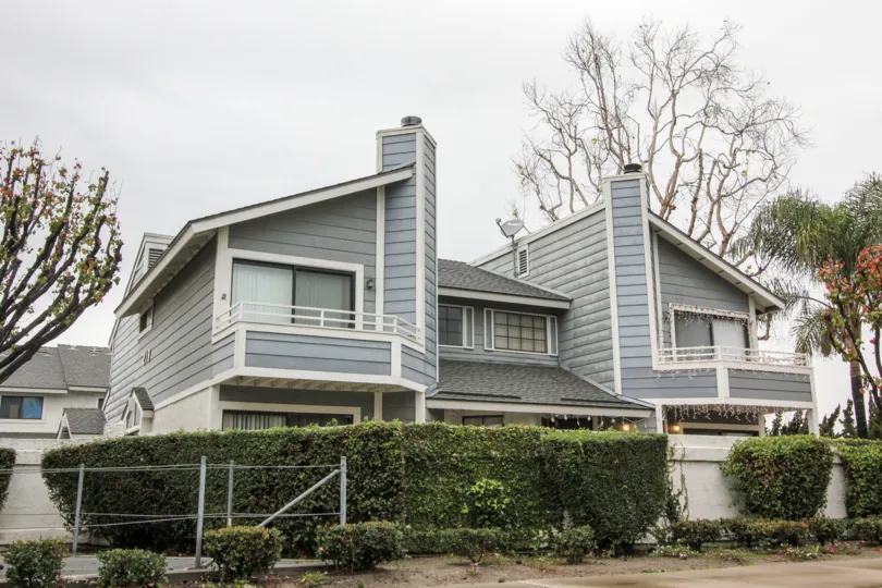 A two-story residence with balconies surrounded by trees and bushes in Carbon Creek