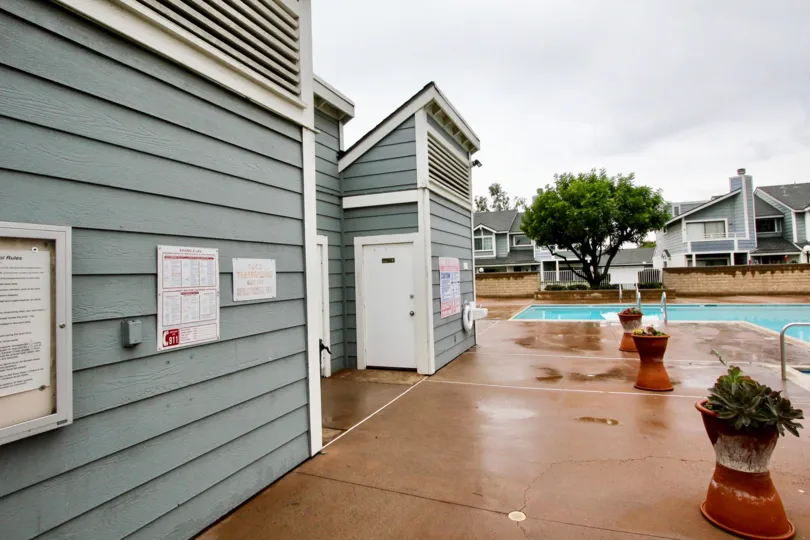 Side of swimming pool with tan pavement next to gray building in Carbon Creek community in Anaheim, California