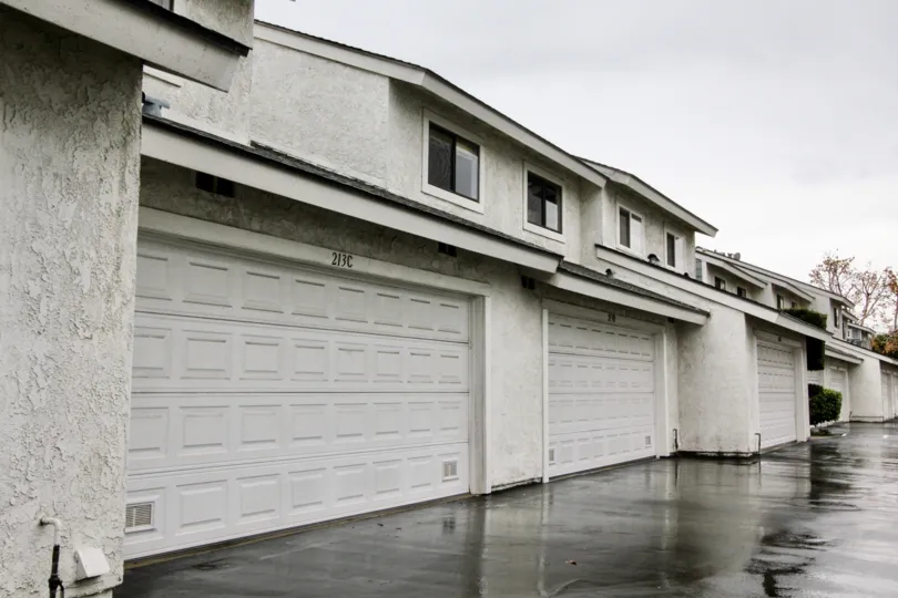 White apartment complex with garages on a rainy day