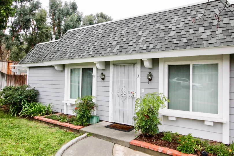 A small and beautiful white and ash color building in the Casa Canon with some flowering plants, shrubs and tree.