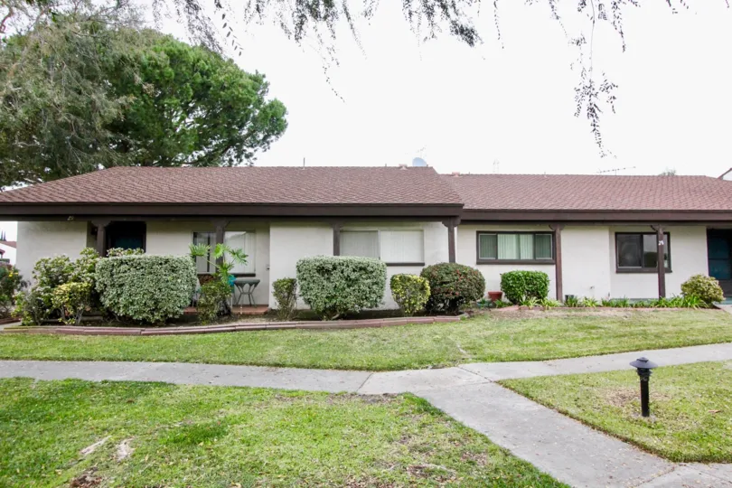 Short white house with brown roof and bushes in Casa Emperador, Anaheim CA