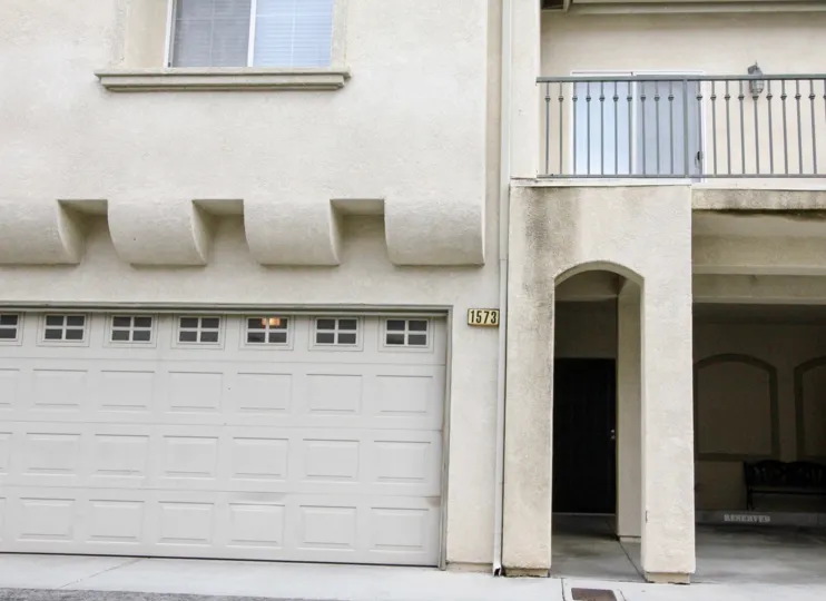 The front of a townhome with a balcony and garage overlooking the street
