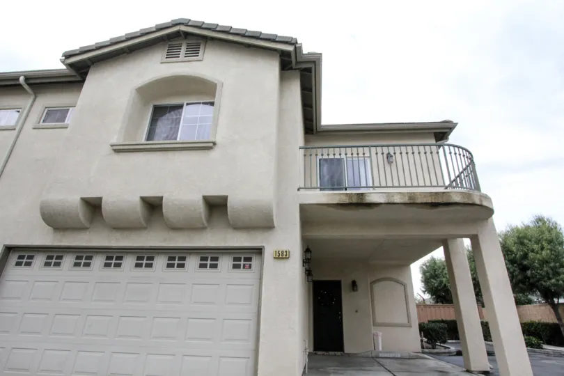 Townhome with garage and balcony in the front and trees to the side